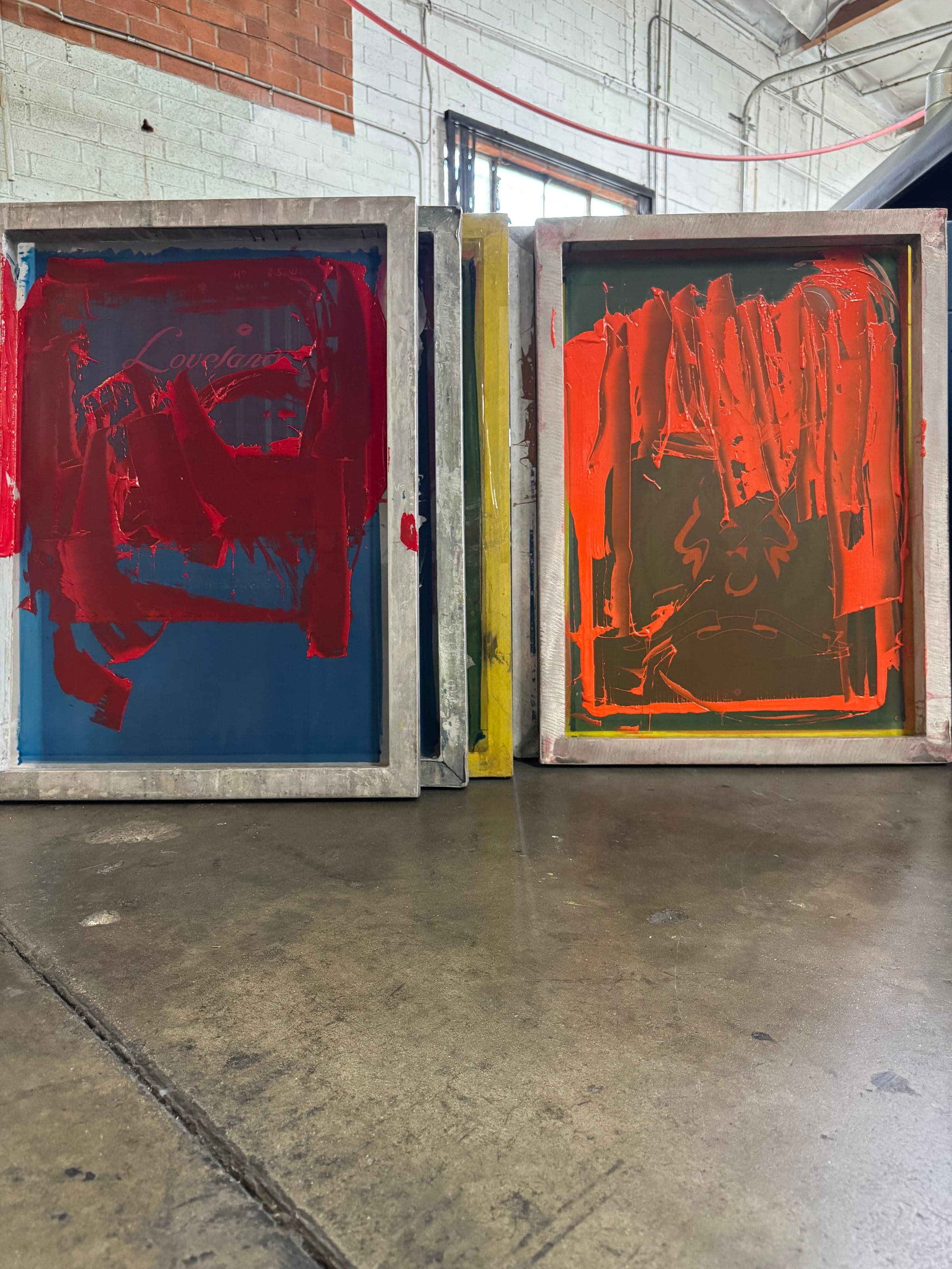 Screen printing screens coated with red and orange ink on the production floor